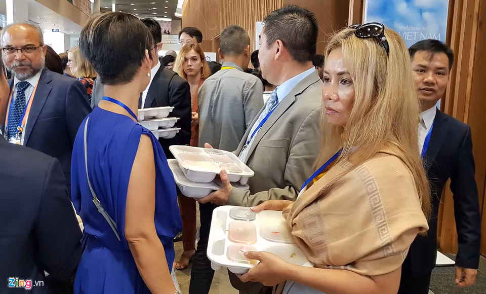 Nhiều người đứng đợi có bàn để đặt hộp cơm lên dùng.