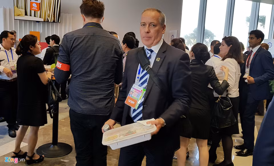 Sau khi nhận cơm từ nhân viên đẩy xe, mỗi người cầm một hộp đi tìm chỗ trống để ăn trưa.