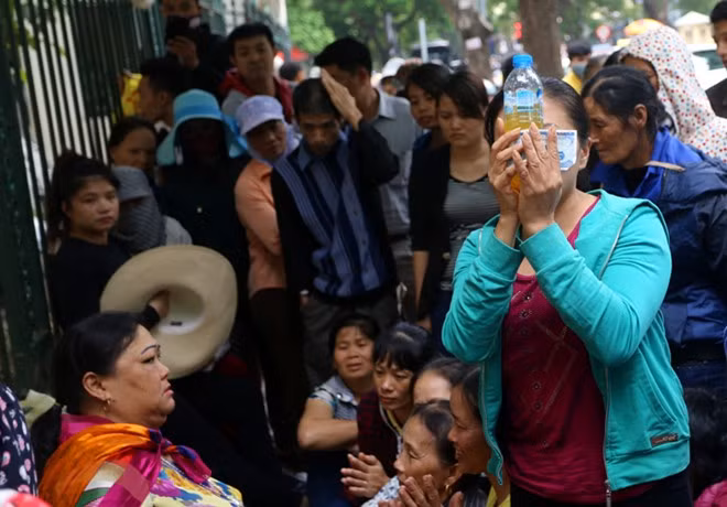 Một người được "thánh chữa bệnh" phát chai nước không rõ nguồn gốc và tiền lộc. "Thánh" nói chai nước này chữa được bệnh rồi căn dặn cách sử dụng.