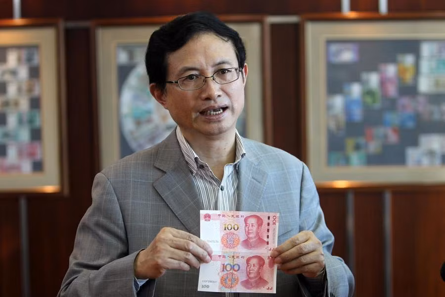 Ông Shao Guowei, Giám đốc công nghệ của công ty in ấn và đúc tiền Trung Quốc cầm tờ tiền giấy cũ so sánh với mẫu tiền mới.