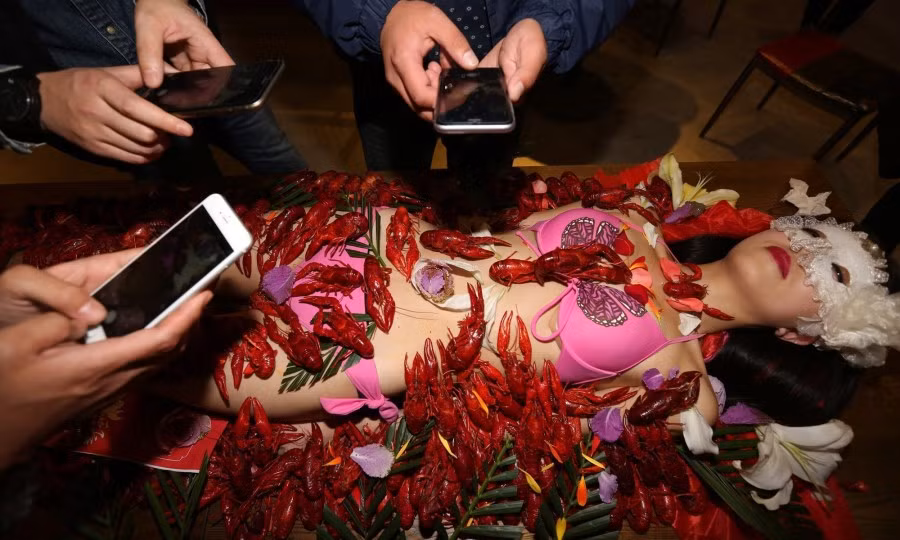 Rất nhiều du khách đã lấy ra điện thoại chụp ảnh bàn tiệc tôm trên người mẫu bikini.