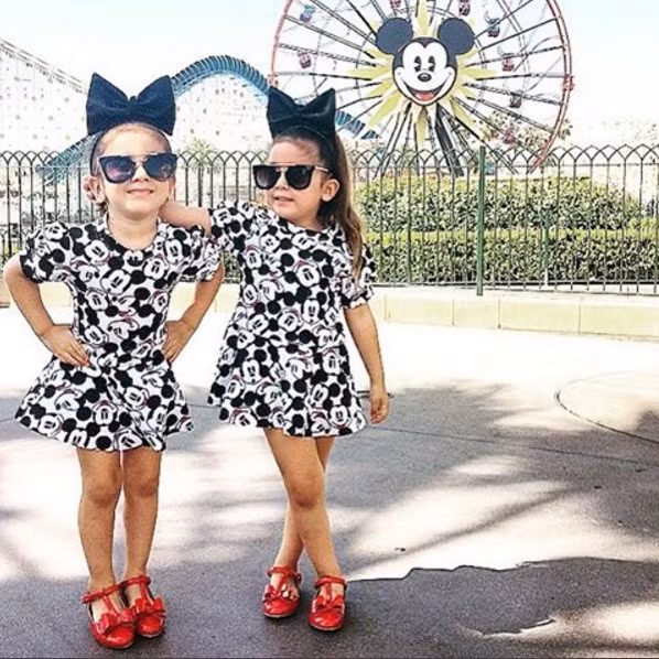 Hai cô bé diện váy, giày và kính hàng hiệu giống hệt nhau trong chuyến thăm công viên Disneyland.