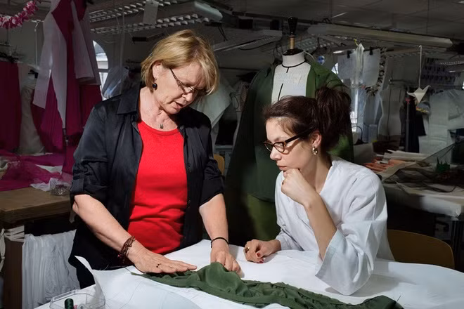 Nghệ nhân Monique (trái) - thợ chính đứng đầu xưởng may - cùng đồng nghiệp bàn về cách may mảnh lụa màu xanh kaki sao cho đúng với thiết kế.