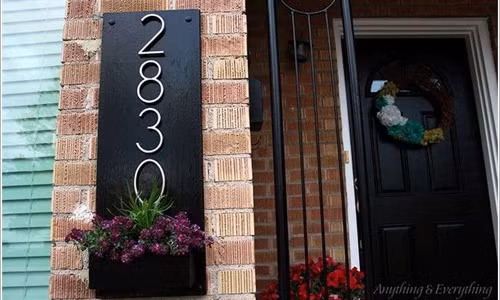 Việc gắn số nhà trên một tấm bảng gỗ trước hiên cũng là cách trang trí nhà cửa ấn tượng mà bạn nên tham khảo.