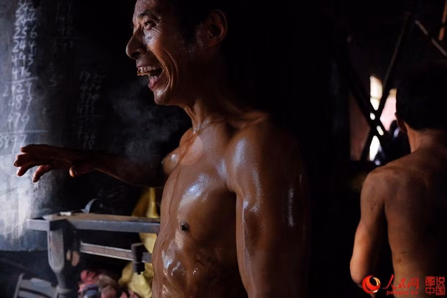 Một công nhân đổ mồ hôi nhễ nhại sau quá trình ép dầu hạt cải tại xưởng.