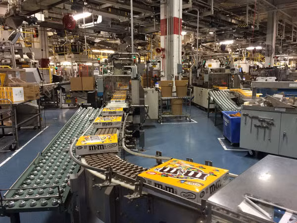 Các hộp kẹo M&amp;M đang lăn ra khỏi dây chuyền sản xuất trong nhà máy ở Hackettstown.