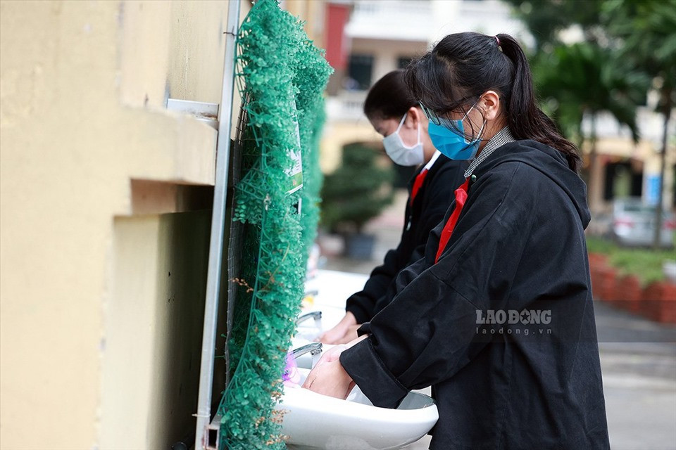 Để công tác phòng dịch diễn ra nhanh chóng, nhà trường đã bố trí lực lượng tình nguyện, nhân viên, giáo viên của trường thực hiện nhiệm vụ kiểm tra thân nhiệt, nhắc nhở học sinh sát khuẩn ngay từ cổng vào. (Ảnh: Lao Động) 
