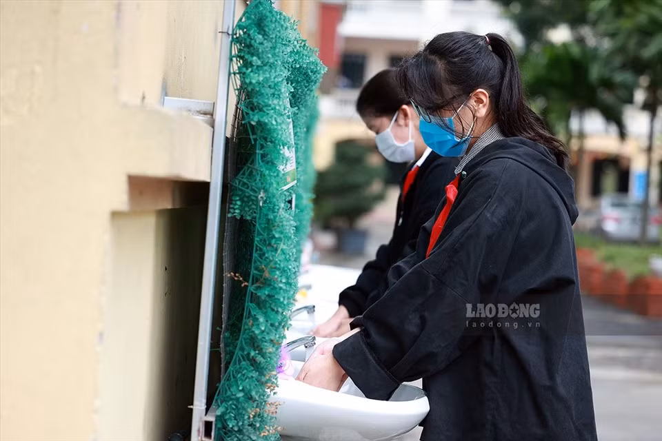 Để công tác phòng dịch diễn ra nhanh chóng, nhà trường đã bố trí lực lượng tình nguyện, nhân viên, giáo viên của trường thực hiện nhiệm vụ kiểm tra thân nhiệt, nhắc nhở học sinh sát khuẩn ngay từ cổng vào. (Ảnh: Lao Động) 