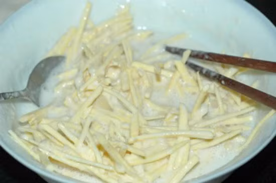 Bước 4: Cho khoai lang vào trộn để khoai được thấm đều bột.