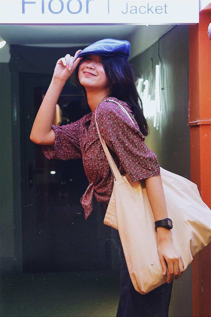 Mũ bê rê, áo sơ mi hoa nhí buộc vạt, quần tối màu cùng phụ kiện là chiếc túi vải giản dị, nhìn Á hậu Bảo Ngọc rất phong cách và cá tính.