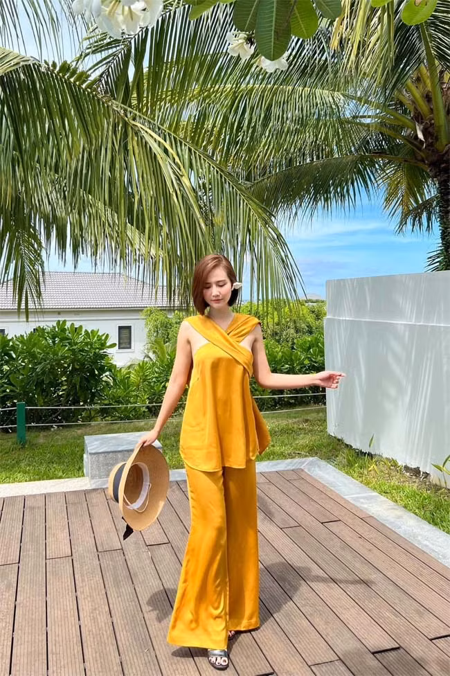 Phan Minh Huyền chọn một bộ quần áo lụa màu vàng không quá kiểu cách trong một chuyến du lịch.