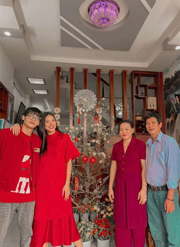 Chiếc váy đỏ đuôi cá dài, tay bồng là trang phục Kim Duyên chọn khi chụp ảnh với gia đình dịp Tết.