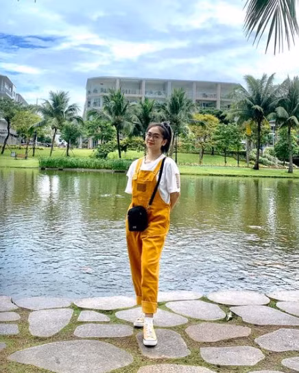 Thiện Nhân nhí nhảnh với set quần yếm vàng, áo phông trắng, giày sneaker.