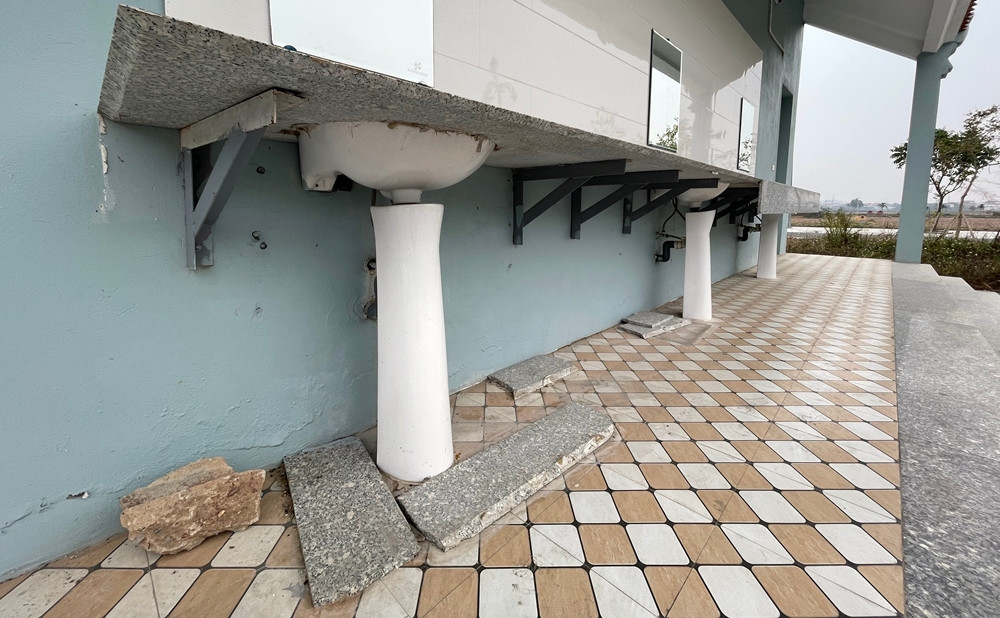 Một phần đá chậu rửa mặt bị rơi vỡ nát. Sơn tường bong tróc.