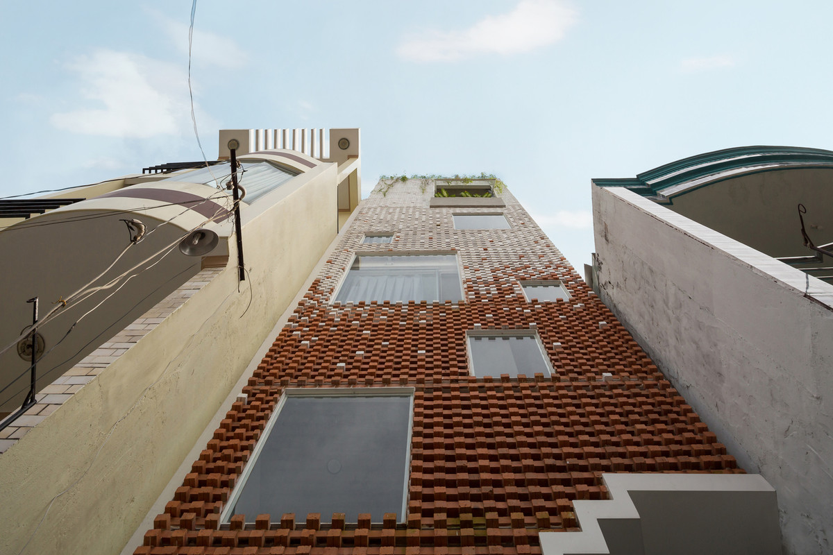 Điểm nhấn của căn nhà là những viên gạch nung, một vật liệu địa phương có khả năng tạo hình linh hoạt, được sử dụng làm “rèm” của mặt tiền.