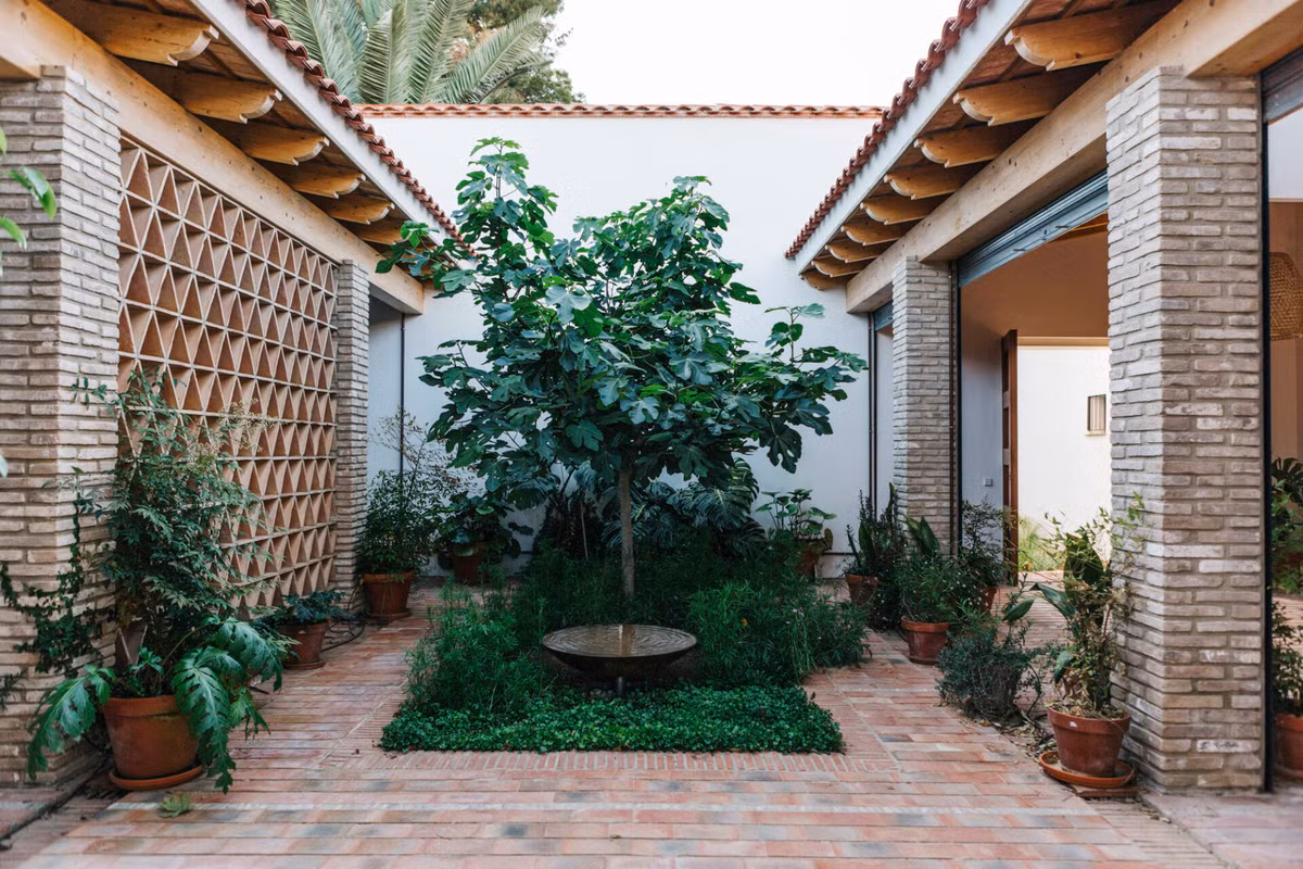 Đi qua cổng là khu vườn nhỏ xanh mướt cùng không gian gạch đất nung thô mộc.