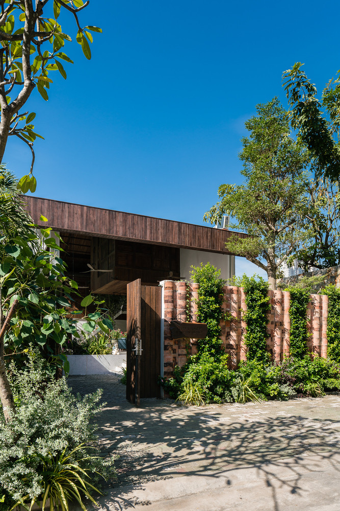 Bên ngoài mặt tiền, gia chủ sử dụng những vật liệu hết sức dung dị như vách gỗ, lớp ngói rêu phong và giàn cây leo xanh mướt.