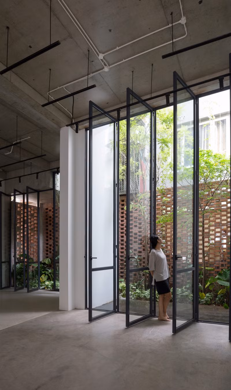 Hai lớp mặt tiền căn nhà gồm lớp ngoài bằng gạch xếp tạo lỗ và lớp trong bằng kính khung sắt. Ảnh: Hoàng Lê.