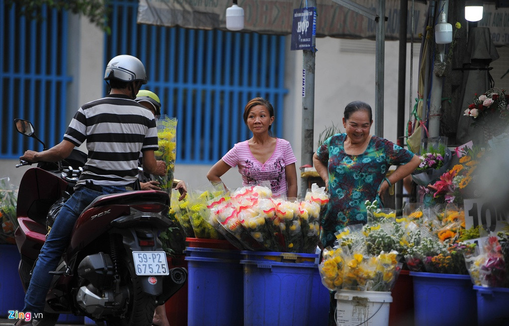 Bà Nguyệt (ngoài cùng bên phải) giới thiệu hoa cho khách chiều muộn ngày 8/3. Bà bán hoa tại khu vực cách chợ hoa Đầm Sen khoảng 100 mét. "Sức mua hôm 7/3 và sáng nay của người dân khá mạnh. Tuy nhiên đến chiều thì giảm hẳn. Tôi định bán đến khoảng 20h tối nay, cố gắng hết hàng" - bà Nguyệt cho biết.
