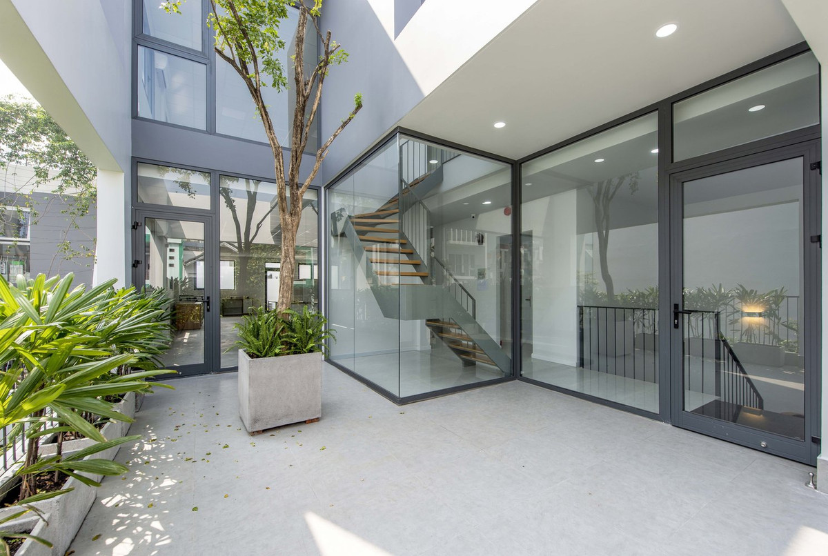 Hệ thống cửa, tường và lan can kính mang đến tầm nhìn ra vườn cây xanh mướt.