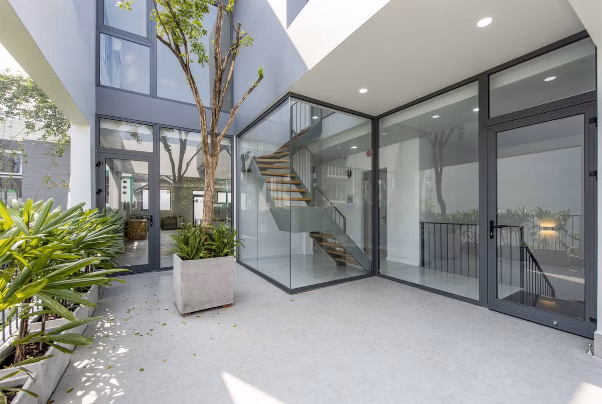 Hệ thống cửa, tường và lan can kính mang đến tầm nhìn ra vườn cây xanh mướt.