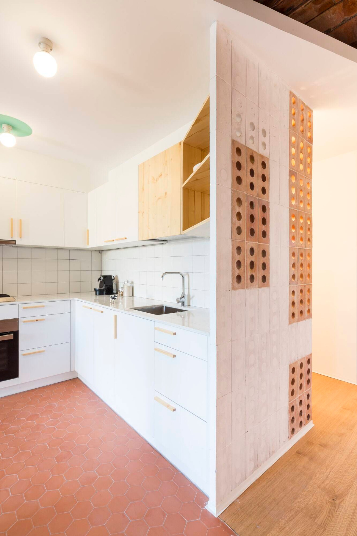 Tủ bếp màu trắng nổi bật trên nền gạch đỏ tạo cảm giác căn nhà như rộng hơn.