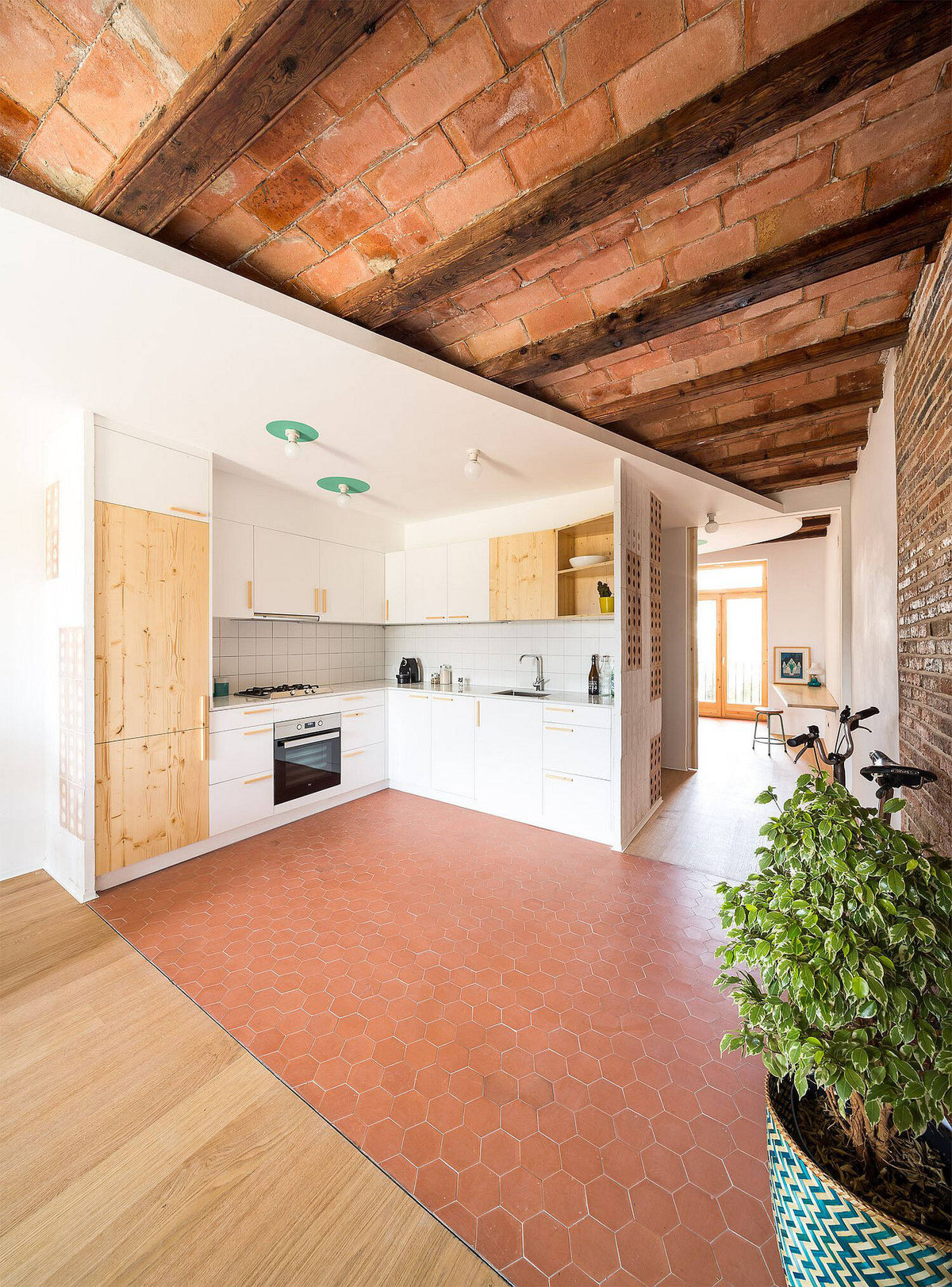 Nhà bếp tách biệt với phòng khách bằng gạch lát sàn màu nâu đỏ.