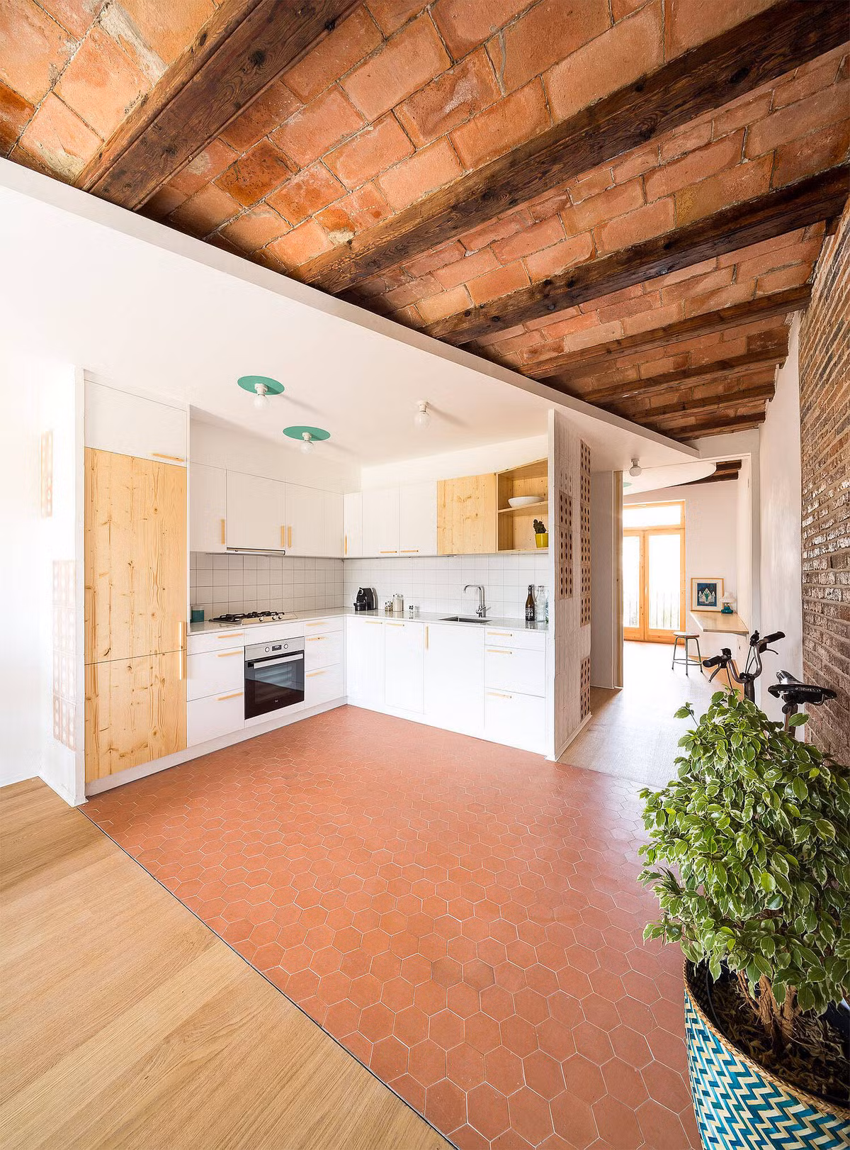 Nhà bếp tách biệt với phòng khách bằng gạch lát sàn màu nâu đỏ.