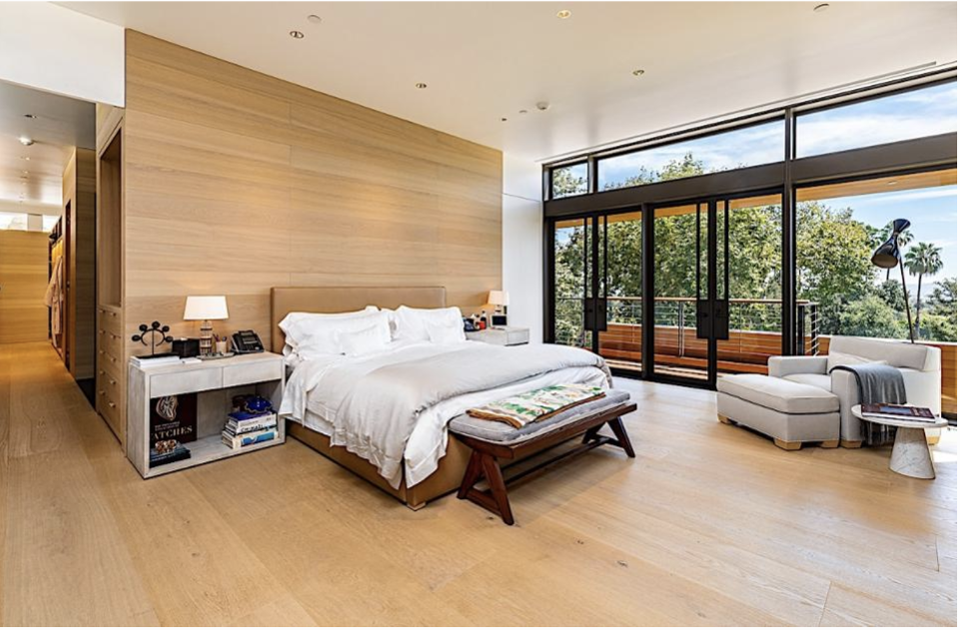 Phòng ngủ được lát sàn bằng gỗ kết hợp với những tấm kính hiện đại nhìn thẳng ra ban công rộng rãi.