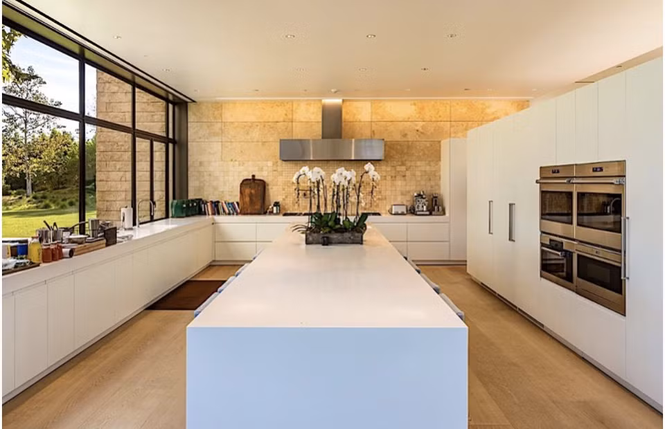 Sàn nhà bếp được lát bằng gỗ sồi, tường lát bằng đá thiên nhiên và tone màu trắng chủ đạo.