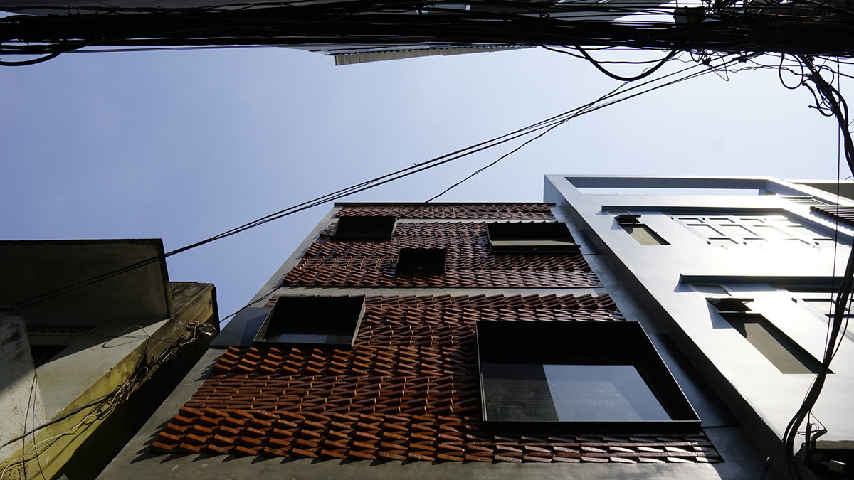 Nằm trên khu đất 36m2, ẩn mình trong một con hẻm nhỏ sôi nổi gần kênh Nhiêu Lộc (TP HCM), ngôi nhà gây chú ý ở mặt tiền sử dụng vật liệu gạch nung.