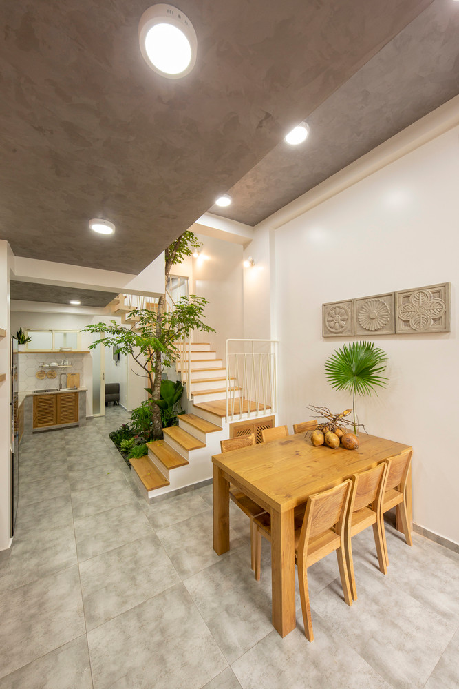 Giữa nhà là cầu thang đi xung quanh cây lớn dưới một mái nhà mờ, chức năng như mảng xanh đem lại sự thoáng mát.