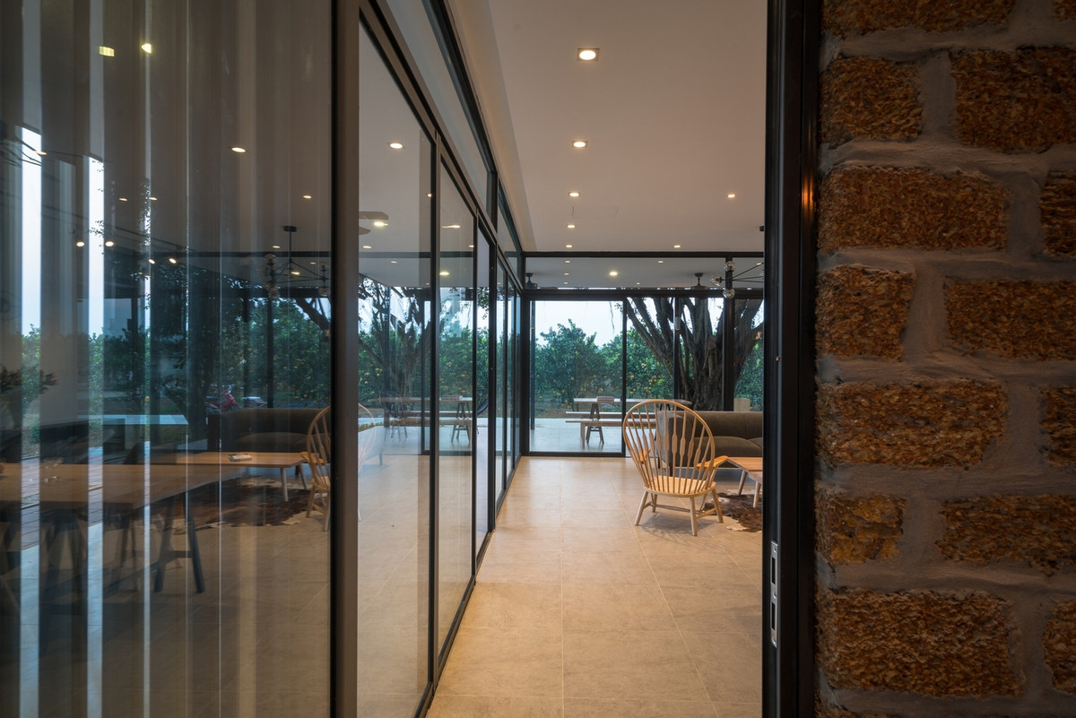 Ngăn cách phòng khách với khu bếp và phòng ngủ là bức tường gạch đá ong mộc mạc. Ảnh: Trieu Chien.