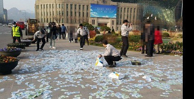 Năm 2016, một phụ nữ Hàn Quốc đã ôm cả đống tiền 22 triệu won (tương đương 400 triệu đồng) đi rải ở quảng trường Seoul để chồng và con trai không thể cướp tài sản của mình. Ảnh: KoreaTimes. Video: Rải tiền lẻ ở đền, chùa: Phản cảm! Nguồn: VTC1