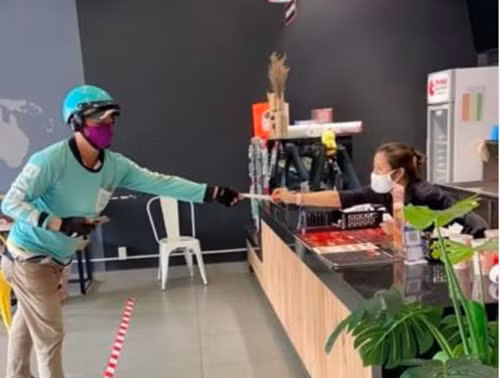 Do đó, nhiều shipper đã có sáng kiến hay để giao hàng cho khách như giữ khoảng cách trên 2m. Ảnh: Nguoiduatin.