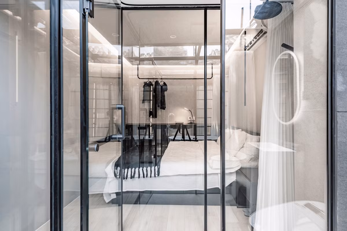 Phòng ngủ đơn giản với gam màu đen - trắng chủ đạo, tạo sự đối lập với không gian trong suốt bên ngoài.