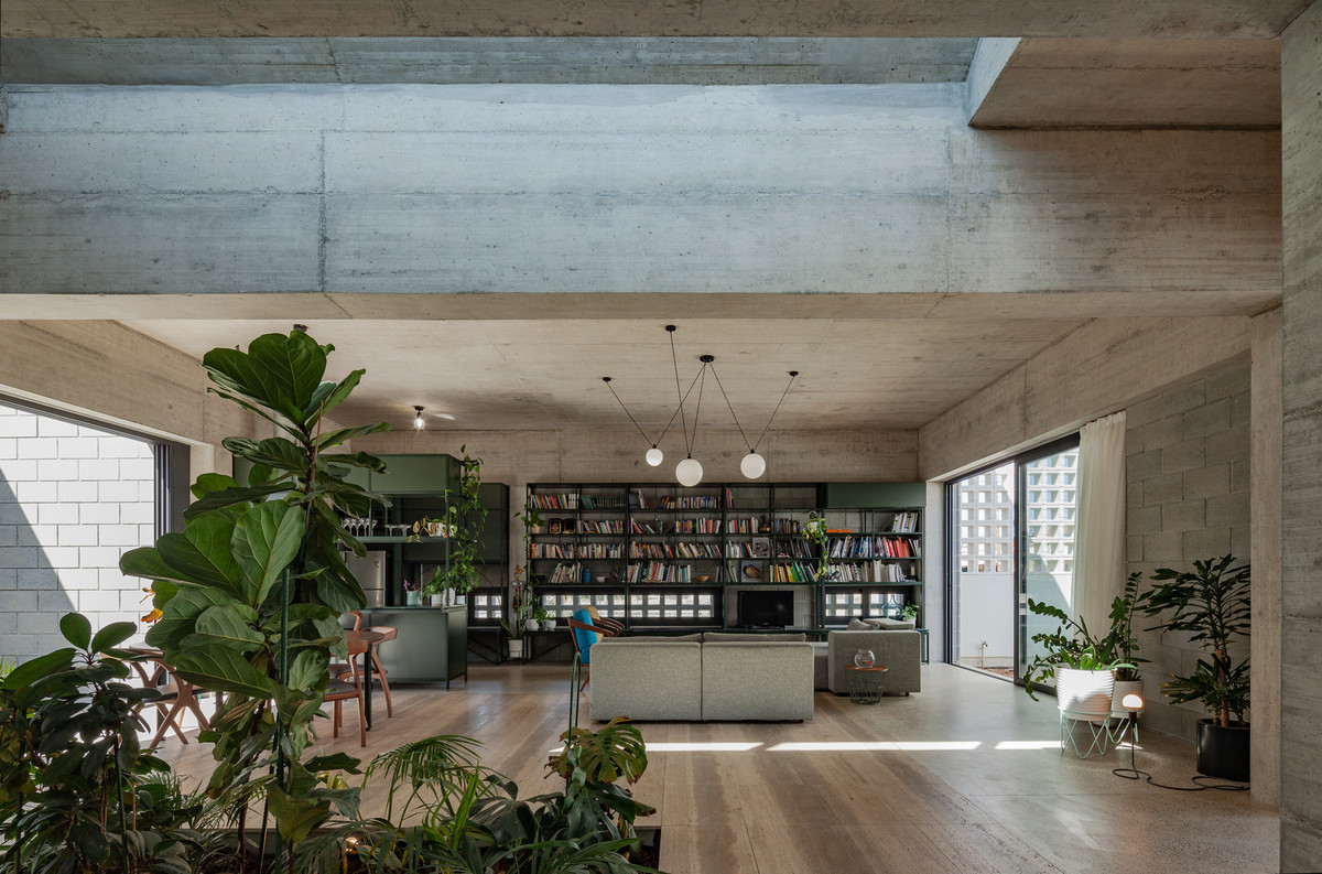 Không gian phòng khách thoáng rộng được trang trí bởi đèn thả trần và giá sách lớn.