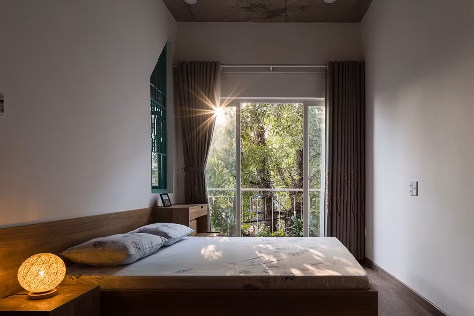 Phòng ngủ có cửa sổ lớn với tầm nhìn xanh mát.