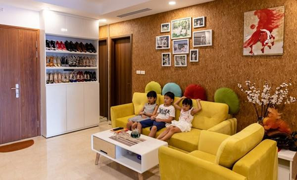 Phòng khách rực rỡ với bộ salon màu vàng tươi, thêm bức tường màu nâu phía sau tạo cảm giác vô cùng ấm cúng.