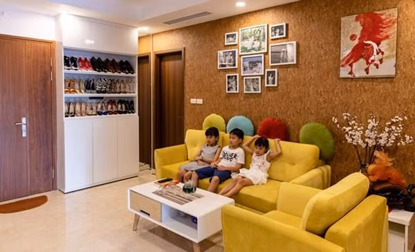 Phòng khách rực rỡ với bộ salon màu vàng tươi, thêm bức tường màu nâu phía sau tạo cảm giác vô cùng ấm cúng.