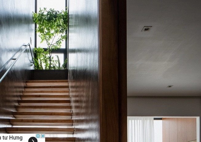 Hai vách tường xi măng ngăn cầu thang với các không gian còn lại để đảm bảo riêng tư. Màu xi măng tối được sử dụng nhằm tạo cảm giác mát mắt, làm tôn màu gỗ, cây xanh.