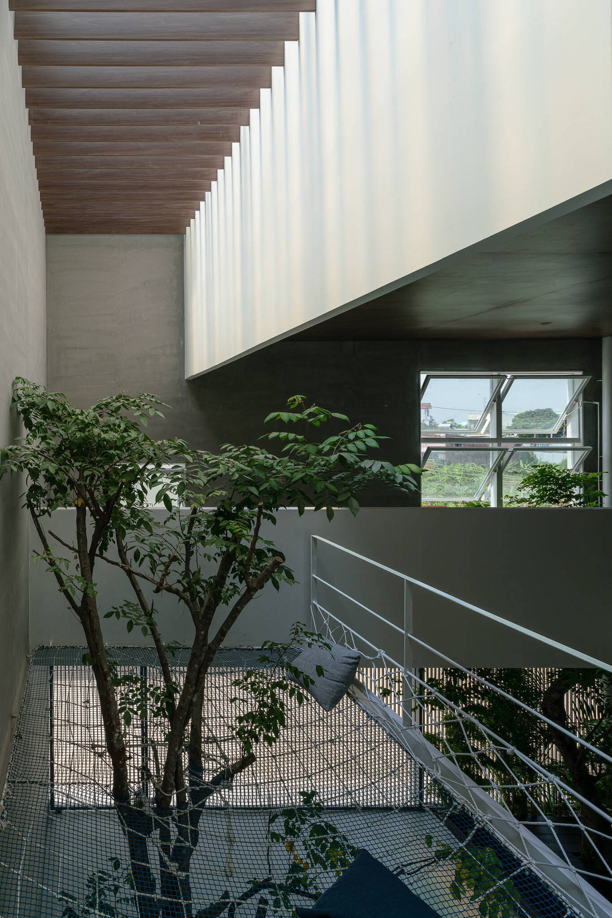 Do gia đình có nhiều thế hệ nên ngôi nhà 2 tầng phải cung cấp đầy đủ công năng từ khu thờ cúng trang nghiêm đến lưới vui chơi của trẻ em ở phía trên bãi để xe.