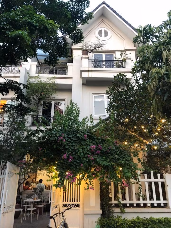 Biệt thự 3 tầng được sơn màu trắng kem, có sân vườn khá rộng rãi, nhiều cây xanh quanh nhà. Ảnh: Khám phá.