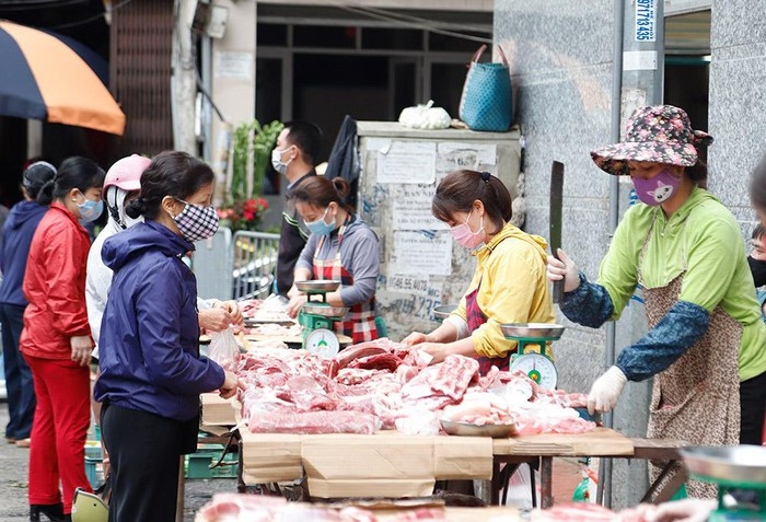 Tại các chợ dân sinh, nhiều người vẫn chưa thực hiện nghiêm việc giữ khoảng cách tối thiểu 2 mét khi mua hàng. Trong ảnh: Người dân đứng sát nhau khi mua hàng tại chợ Gia Lâm (quận Long Biên).