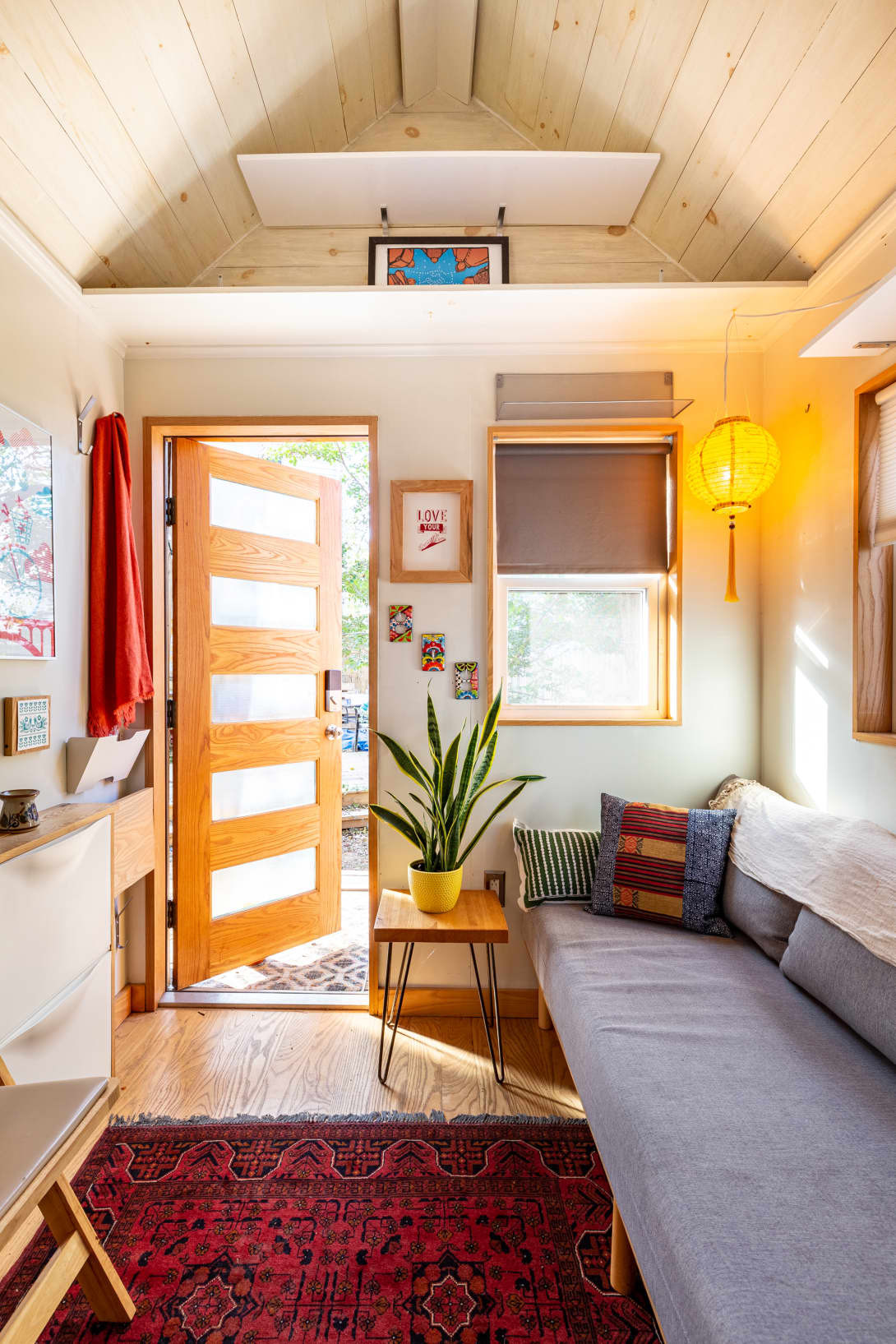 Không gian phòng khách gồm chiếc ghế sofa nhỏ với những chiếc gối trang trí họa tiết tươi sáng.