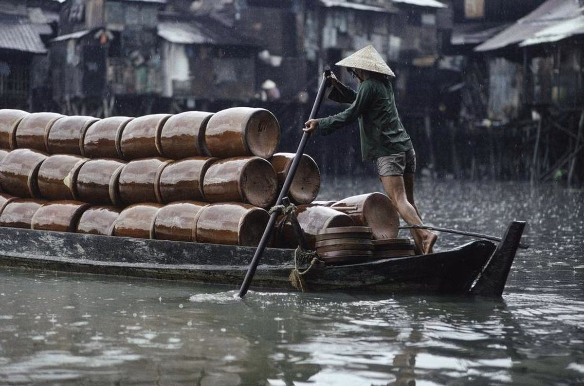 Người phụ nữ chèo thuyền chở đầy những chiếc lu gốm.