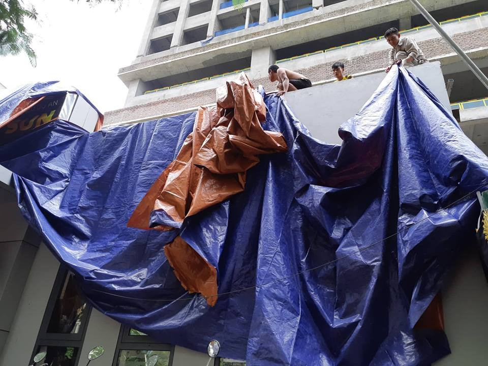 Trong khi đó, các công nhân tại đây khẩn trương sử dụng bạt phủ kín hiện trường.