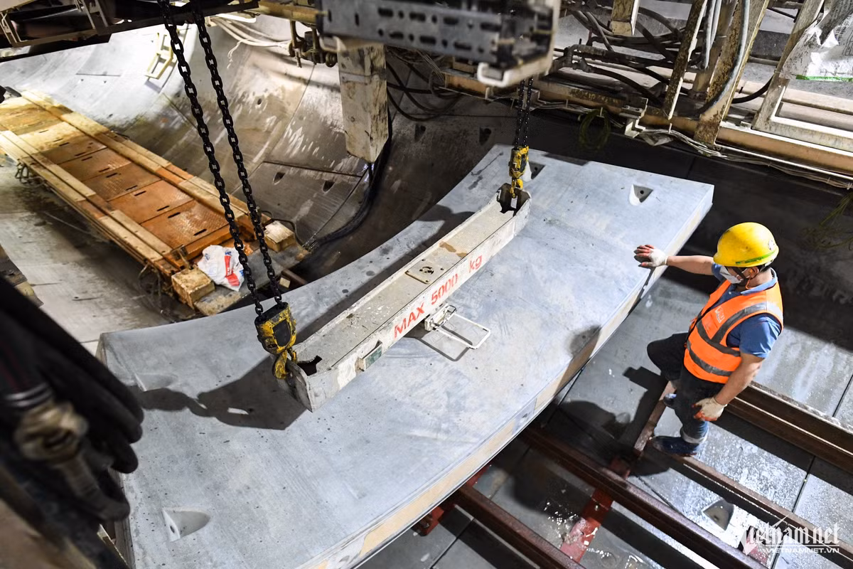 Cứ đào được 1,5m, mũi khoan lại tạm dừng hoạt động để lắp vỏ hầm. TBM khoan tới đâu, bộ phận vỏ hầm sẽ được thi công lắp đặt tới đó. Song song, các hạng mục khác của công trình cũng được hoàn thiện theo phương pháp cuốn chiếu. Các tấm vỏ hầm được đưa vào vị trí nhờ một cánh tay robot.