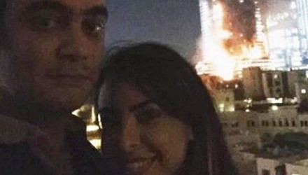 Cặp đôi chụp ảnh trước khách sạn cháy. Ảnh: News