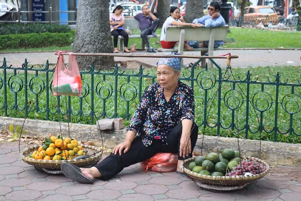 Người phụ nữ bên gánh hoa quả lúc không có khách.